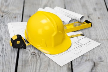 Yellow hard hat and blueprints on wooden