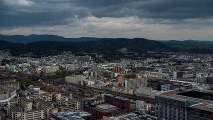 Fototapeta na wymiar Aerial shots of the city of Kyoto. Skyscrapers and buildings expand out into the distance of the Japanese city as a stormy sky and clouds form over the cityscape.