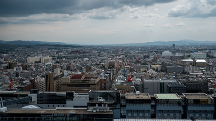 Obraz premium Aerial shots of the city of Kyoto. Skyscrapers and buildings expand out into the distance of the Japanese city as a stormy sky and clouds form over the cityscape.