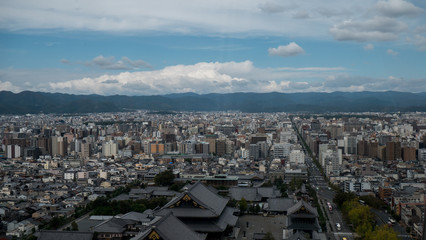 Obraz premium Aerial shots of the city of Kyoto. Skyscrapers and buildings expand out into the distance of the Japanese city as a stormy sky and clouds form over the cityscape.