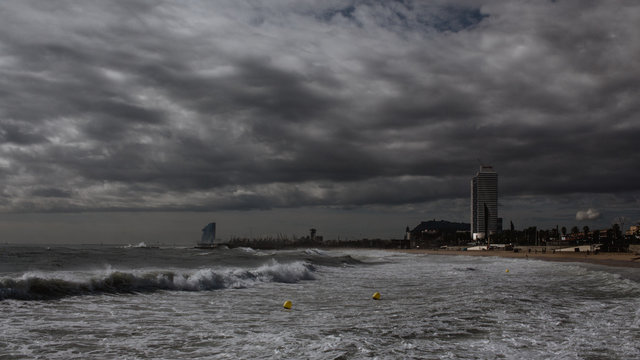 Grey sky and waves on the city of Barcelona. 