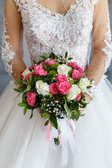 Bride in a lace dress holding a wedding bouquet of white and pink roses