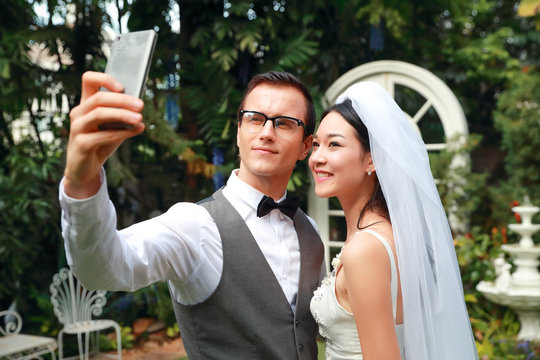 bride and groom use cell phone do self portrait on pre wedding day