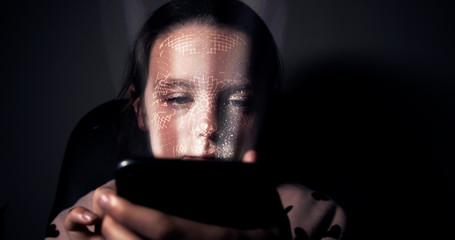 Young girl having her face scanned by her smart phone. Facial recognition concept