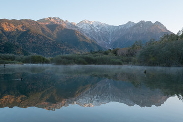 Obraz premium 紅葉の上高地・大正池から見た朝日に照らされる穂高連峰