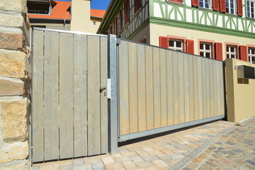 Neues Einfahrtstor in der Hauszufahrt vor denkmalgeschütztem Fachwerkhaus, verkleidet mit lasierten Holzplanken