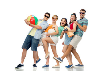 Fototapeta premium summer holidays and people concept - group of happy smiling friends in sunglasses with beach ball, volleyball, towel and camera over white background