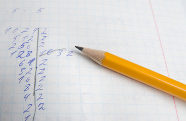 The pencil is on the notebook of the student. Close up.