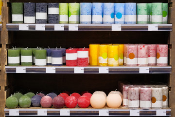 Candles for sale in a interior decorating store. Сoloured variety paraffin candles in cozy candle...