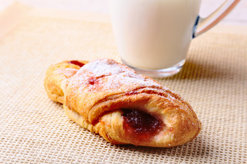 Easter breakfast with traditional hot cross bun with jam and glass with milk. From above on wooden table.