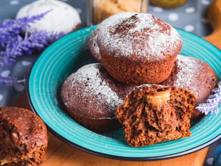 Chocolate home made baked muffins with pears and icing sugar on winter background