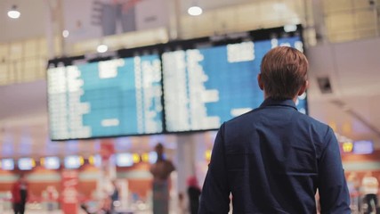 Shot back young man in modern airport terminal travelling guy wearing smart casual style clothes walking away airline arrival flight journey lifestyle passenger plane tourist hall indoors - Powered by Adobe