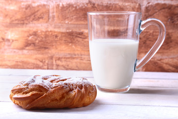 Chocolate and powdered sugar cream puff rings, choux pastry and glass with milk