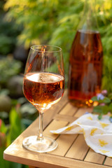 Cold rose wine in glasses served on outdoor terrace in garden with flowers in sunny day