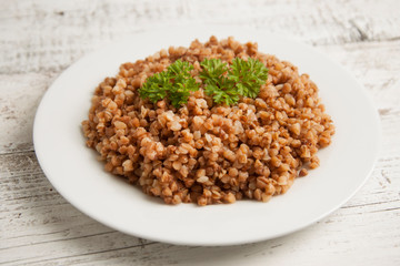 Cooked buckwheat on white wooden background. Healthy food.
