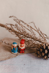New Year, Santa Claus (Father Frost) and Snow Maiden, Christmas card. Plasticine figurines on a textile linen surface. Cone and dry flower like decoration.