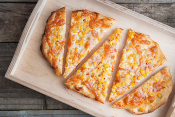 Colorful sliced homemade pizza for kids with cheese and sweet corn. Italian traditional food. Top view.