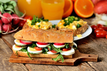 Baguette sandwich with egg, arugula salad, tomatoes and radish