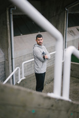 Sporty man taking a workout rest for drinking water. Male athlete on urban training.