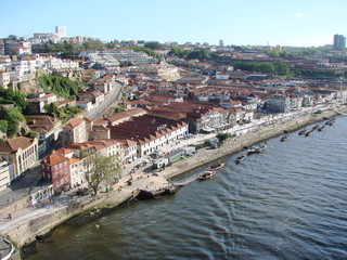 Fototapeta na wymiar Landscape from the bird's eye view of buildings and streets of the city of Porto on the banks of the river against the blue sky.