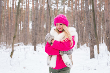 Fashion and people concept - Attractive young woman standing in pink warm jacket in winter snowy park