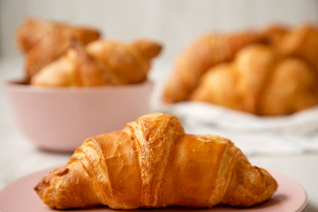 Fresh croissants with golden crust on white wooden table, side view. Close-up. Selective focus.