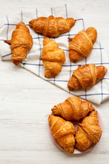 Fresh croissants with golden crust on white wooden table, overhead view. From above, flat lay. Copy space.