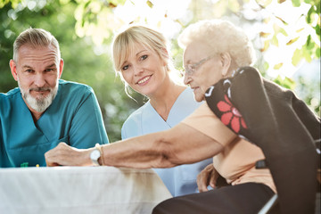 Pfleger Pflegerin spielen mit Seniorin ein Brettspiel