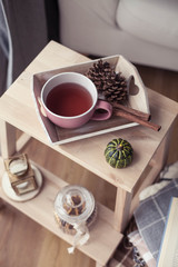 Plaids, a cup of hot tea, autumn decor, a book, a pumpkin on a wooden chair. Cozy, autumn decor. Autumn interior, sofa. Autumn. Winter.