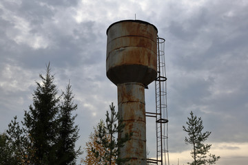 An old rusty water tower stands among the trees
