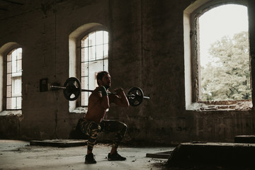 Athletic man doing front squat in an old building