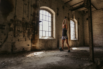 Athletic woman doing kettlebell swing in an old building