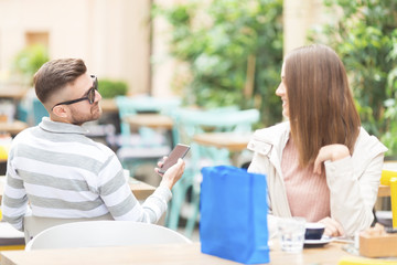 Young beautiful people in city cafe garden flirting