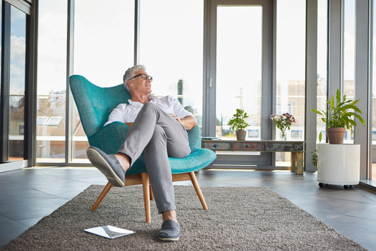 Mature man relaxing in armchair at the window at home