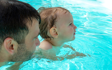 Father and child are having fun in pool. Dad and son are swimming indoor pool. Father teachs son to swim. Concept of kids sport, family summer vacation. Concept of healthy holiday and family activity.