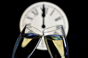 CELEBRATION OF THE NEW YEAR, glasses raising with champagne with the clock unfocussed