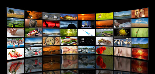 Wall of stacked TV screens with various motifs on a black background - 229916369