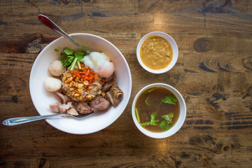 Dry boiled rice with braised pork rip, pork meatball, boiled egg and soup, sauce favorite delicious Asian food on the wooden table