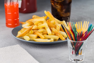 French fries potatoes fried on a plate with decorative colored forks