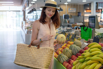 Young woman on the market choosing bio fruit. Housewife buying melon on the food glocery store. Concept of healthy bio organic food.