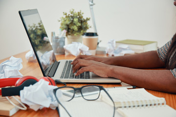 Crop side view of African American businesswoman at table using laptop and typing 