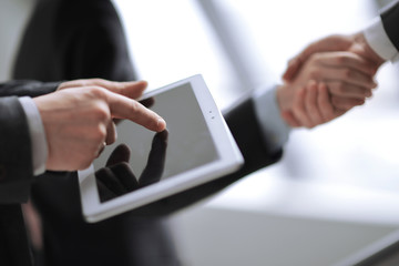 close up.businessman using digital tablet on background of handshake of business partners