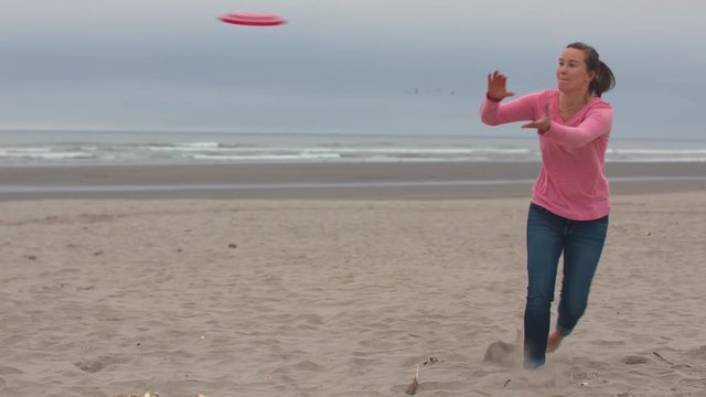 Woman in a Pink Shirt Running to Catch a Frisbee