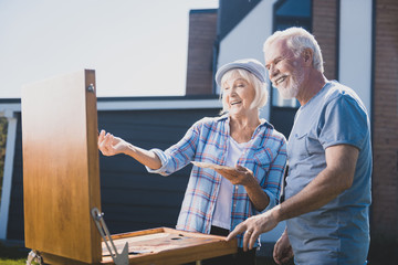 Laughing couple. Elderly happy couple laughing out loud while drawing still life in their garden...