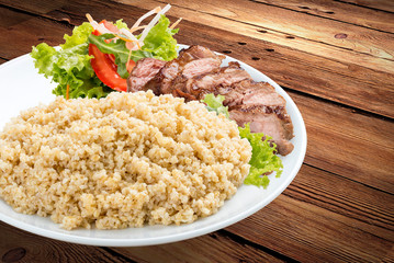 Millet porridge with pork grilled. On a wooden background