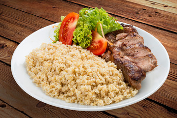 Millet porridge with pork grilled. On a wooden background