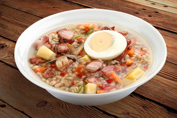 Pearl soup with bacon and egg. On a wooden background