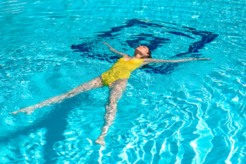 Woman in yellow swimsuit lying on the water in the pool, star, relaxation, relaxation, Wellness