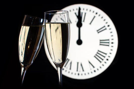 CELEBRATION OF THE NEW YEAR, glasses raising with champagne with the clock unfocussed