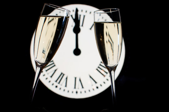 CELEBRATION OF THE NEW YEAR, glasses raising with champagne with the clock unfocussed